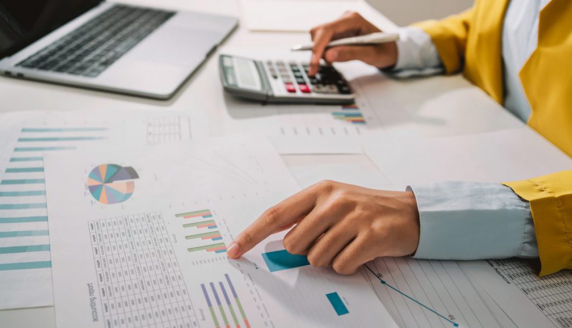 Woman accountant use calculator and computer with holding pen on